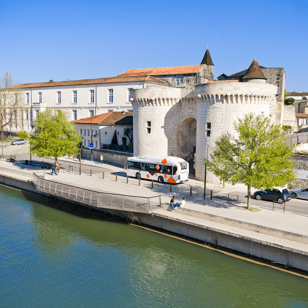 2026-un bus passe sur les quais de Cognac devant la Porte Saint-Jacques, ciel bleu. 